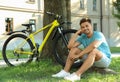 Handsome young man sitting near bicycle on green Royalty Free Stock Photo