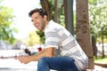 Handsome young man sitting outdoors with mobile phone and laughing Royalty Free Stock Photo