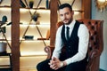 Handsome young man sitting and posing in armchair in modern luxury interior Royalty Free Stock Photo