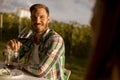 Handsome young man sitting by the table and drinking red wine in the vineyard Royalty Free Stock Photo