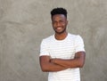 Handsome young man smiling with arms crossed by wall Royalty Free Stock Photo