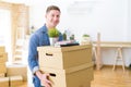 Handsome young man smiling happy moving to a new home, very excited holding cardboard boxes at new apartment Royalty Free Stock Photo