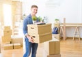 Handsome young man smiling happy moving to a new home, very excited holding cardboard boxes at new apartment Royalty Free Stock Photo