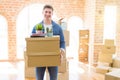 Handsome young man smiling happy moving to a new home, very excited holding cardboard boxes at new apartment Royalty Free Stock Photo