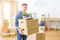 Handsome young man smiling happy moving to a new home, very excited holding cardboard boxes at new apartment Royalty Free Stock Photo