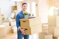 Handsome young man smiling happy moving to a new home, very excited holding cardboard boxes at new apartment Royalty Free Stock Photo