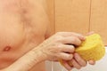 Handsome young man soaping yellow sponge with soap Royalty Free Stock Photo