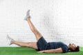 Handsome young man in sportswear doing scissors exercise on artificial green lawn Royalty Free Stock Photo