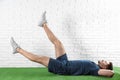 Handsome young man in sportswear doing scissors exercise on artificial green lawn near Royalty Free Stock Photo