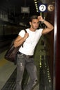 Handsome young man standing against wall in train or subway station Royalty Free Stock Photo