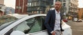 Handsome young man standing near car on city street Royalty Free Stock Photo