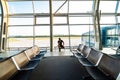 Handsome young man talking on the phone is standing near the panoramic window in airport terminal while waiting for the flight Royalty Free Stock Photo