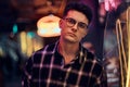 A handsome young man standing at night in the street. Illuminated signboards, neon, lights. Royalty Free Stock Photo