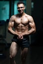 Handsome young man standing strong and flexing muscles in gym Royalty Free Stock Photo