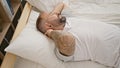 Handsome young man suffering from excruciating cervical pain, lying in bed touching neck with agony in his bedroom Royalty Free Stock Photo