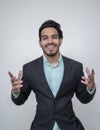 Handsome young man in suit smiling keeping arms outstretched and looking at camera while standing against white background Royalty Free Stock Photo