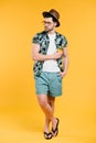 handsome young man in summer outfit holding glass bottle of refreshing beverage and looking away