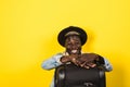 Handsome young african man in summer outfit holding suitcase and looking away isolated on yellow background Royalty Free Stock Photo