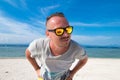 Handsome young man with sunglasses against bright beach background and the blue Indian ocean. There is a volcano Agung Royalty Free Stock Photo