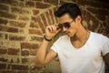 Handsome young man with sunglasses, outdoors next to brick wall Royalty Free Stock Photo