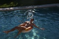 Handsome young man in swimware floating in a pool at sunset