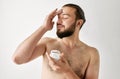 Handsome young man taking care of his skin over grey studio background. Bearded man. Royalty Free Stock Photo