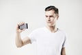 Handsome young man taking picture by mobile phone, isolated on white background, wearing white t-shirt. Royalty Free Stock Photo