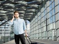 Handsome young man talking on mobile phone at airport with bags Royalty Free Stock Photo