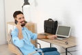 Handsome young man talking on phone while working at table with laptop Royalty Free Stock Photo
