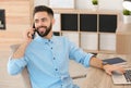 Handsome young man talking on phone while working at table with laptop Royalty Free Stock Photo