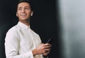 Handsome young man texting messages from his cellphone over black studio background, with wireless earphones. Royalty Free Stock Photo