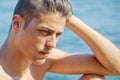 Handsome young man thinking next to the sea