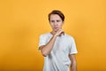 Handsome young man is thinking propping his chin with his hand in white t shirt Royalty Free Stock Photo