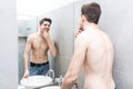 Starting new day with smile. Handsome young man touching his hair with hand and smiling while standing in front of the mirror Royalty Free Stock Photo