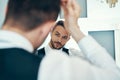 Handsome young man touching his hair with hand standing in front of the mirror Royalty Free Stock Photo