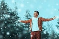 Handsome young man tourist standing on snowy mountain top in winner pose with raised hands enjoying view and achievement on bright Royalty Free Stock Photo