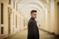 Handsome young man under cloisters in Italian city at night