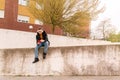 Handsome young man using his mobile phone sitting on a city wall, with plenty of copy space. Street life concept Royalty Free Stock Photo