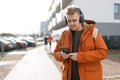 A handsome young man using his phone with headphones and standing on the street in the city. Music lover enjoying music Royalty Free Stock Photo