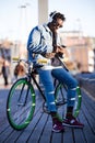 Handsome young man using mobile phone and fixed gear bicycle in the street. Royalty Free Stock Photo