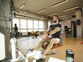 Young man using seated row machine in the gym