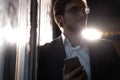 Handsome young man using smart phone during night. Closeup face of businessman messaging on cellphone at night in cafe.