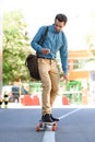 handsome young man using smartphone and riding longboard Royalty Free Stock Photo