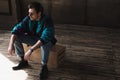 handsome young man in vintage windcheater sitting on wooden box Royalty Free Stock Photo