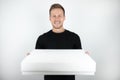 Handsome young man wearing black t-shirt holding parcel in paper box for delivery on isolated white background Royalty Free Stock Photo