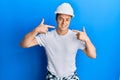 Handsome young man wearing builder uniform and hardhat smiling cheerful showing and pointing with fingers teeth and mouth Royalty Free Stock Photo