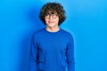 Handsome young man wearing casual clothes and glasses looking away to side with smile on face, natural expression Royalty Free Stock Photo