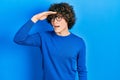 Handsome young man wearing casual clothes and glasses very happy and smiling looking far away with hand over head Royalty Free Stock Photo