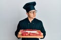 Handsome young man wearing chef uniform holding board with raw meat smiling looking to the side and staring away thinking Royalty Free Stock Photo