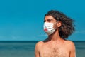 Handsome young man wearing face mask and medical gloves outdoors portrait on the beach Royalty Free Stock Photo